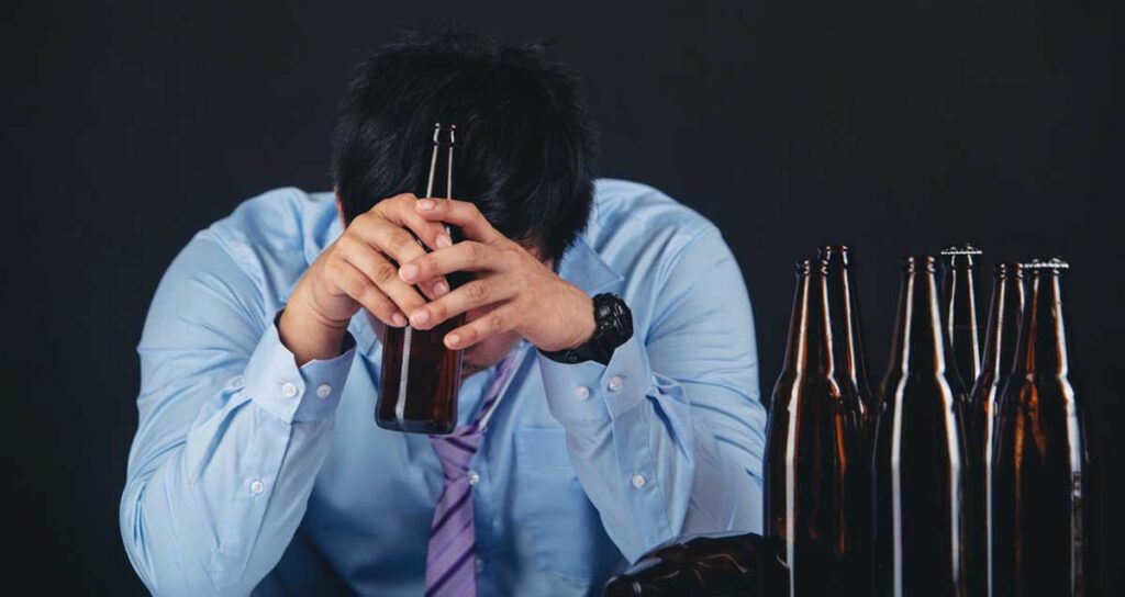 Guy Holding a Bottle of Alcohol showing Symptoms of Alcohol Withdrawal