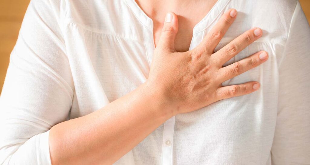 Woman with a hand on her chest with a lifestyle Adjustments to Alleviate Heartburn